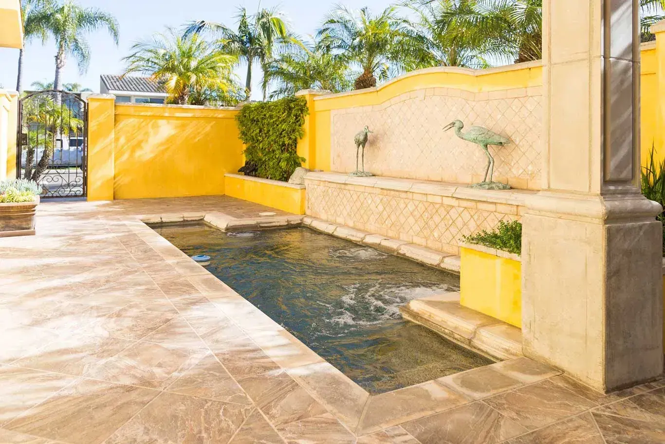 A swimming pool with a fountain in the backyard of a house.